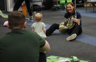 woman playing instrument in front of toddler