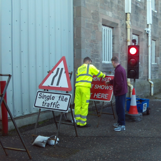 men putting up road work  signs